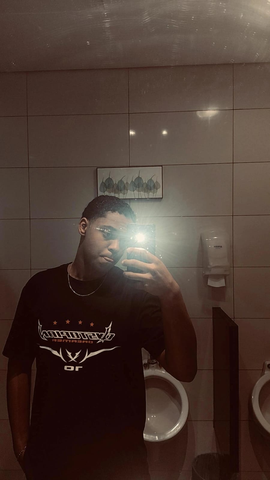 Foto de homem sorrindo ,usando óculos e camiseta preta com cavaque e fundo amarelo